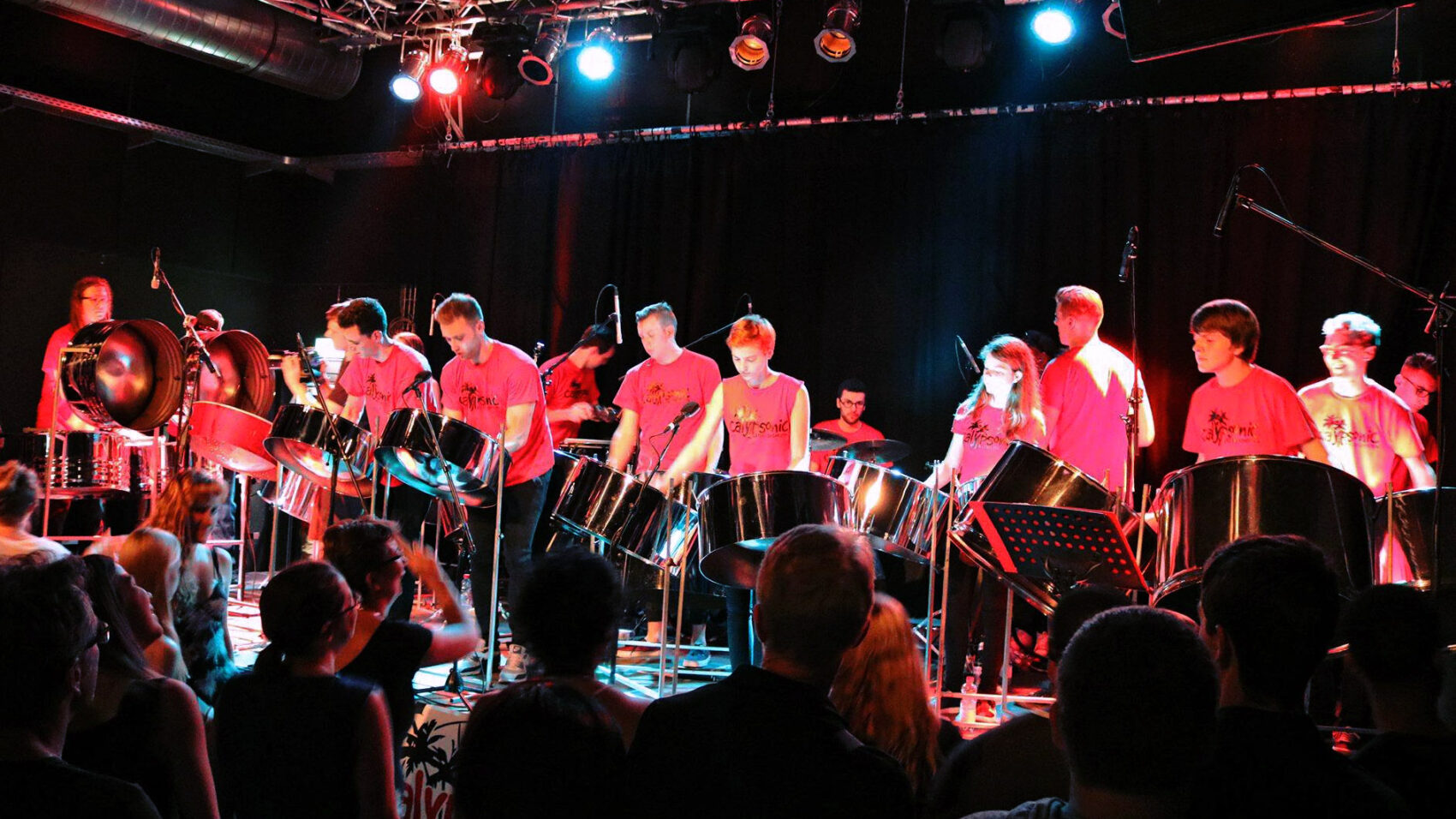 Junge Steelband-Musiker*innen in roten T-Shirts auf der Bühne