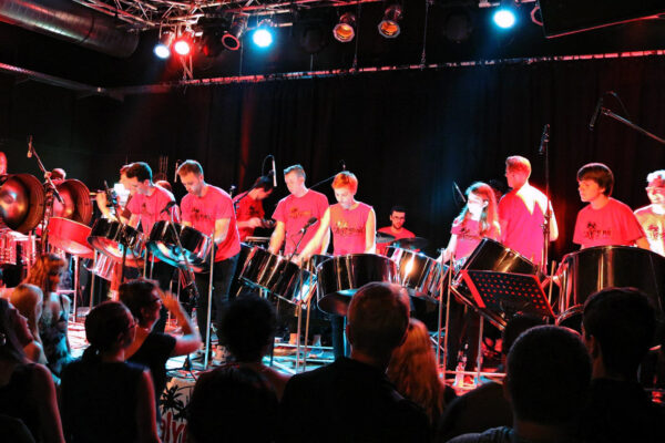 Junge Steelband-Musiker*innen in roten T-Shirts auf der Bühne